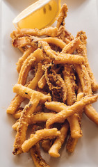 Calamares tradicionales españoles, rebozados, popularmente llamados Rabas, en Santander, Cantabria, España, servidos en plato blanco con rodaja de limón. 