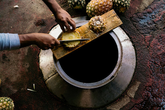 Overhead view of mans hands cutting pineapple outdoors