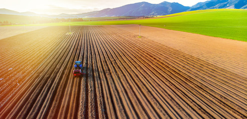 Farmer in tractor preparing land with seedbed cultivator in farmlands. Tractor plows a field....