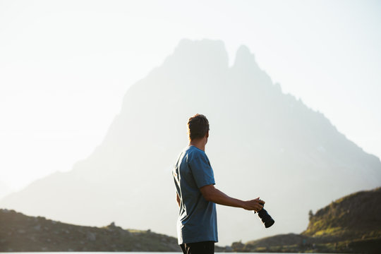 Unrecognizable man taking photo of mountain landscape
