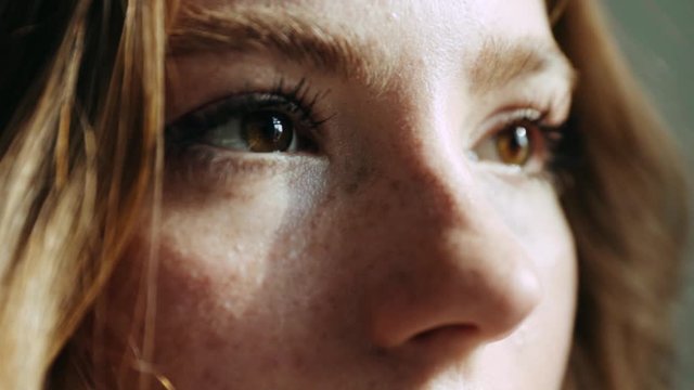 Close-up shot of woman brown eye with light make-up opening and looking at the sun slow motion