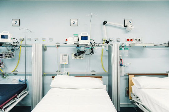 Equipped Intensive Care Unit With Beds Made Up For Patients And Metal Trays For Medical Needs