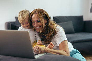 mature woman with her grandchild using laptop computer at her home
