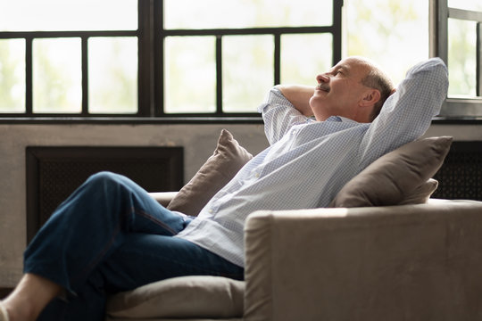 Happy senior hispanic man relaxing on sofa at home