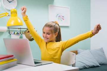 schoolgirl using laptop computer while sitting table in her room