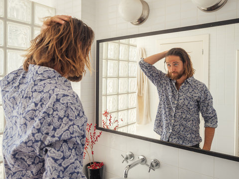 Handsome male checking hairstyle in mirror reflection