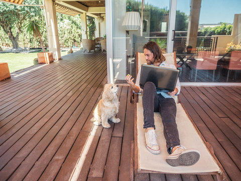 Man with laptop giving apple core to dog