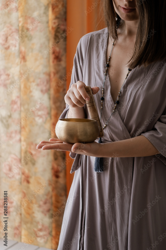 Wall mural Woman holding in hands singing bowl