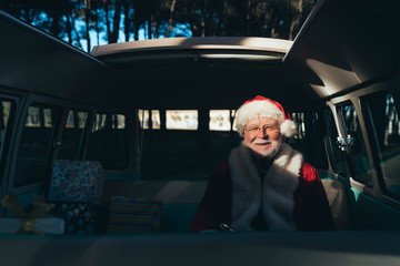 Man dressed as Santa Claus sitting in van with gifts
