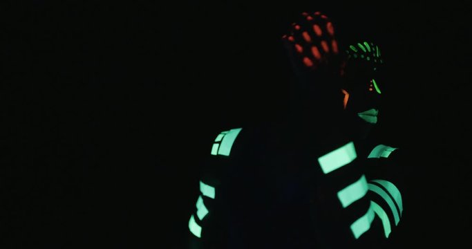 Studio, slow motion, close-up of a neon-painter dancing 