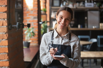Head shot portrait of smiling waitress ready to take customer order - obrazy, fototapety, plakaty
