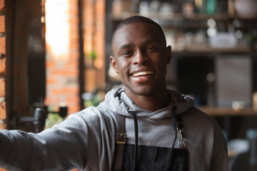 Head shot portrait of African American smiling waiter taking selfie