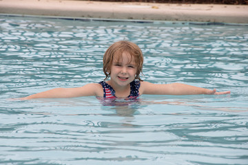 Little girl smiling while playing in swimming pool