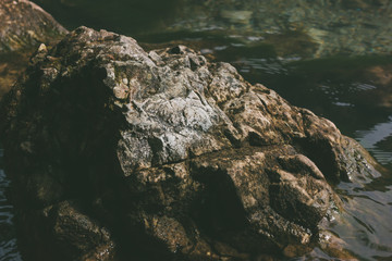 Stones in the clear water of the lake. Covered with moss and algae. Calm expanse of water with shallow waves.