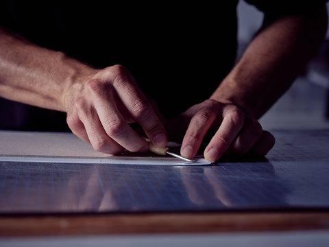 Faceless man working in bookmaking studio and measuring cover for book using pencil and ruler