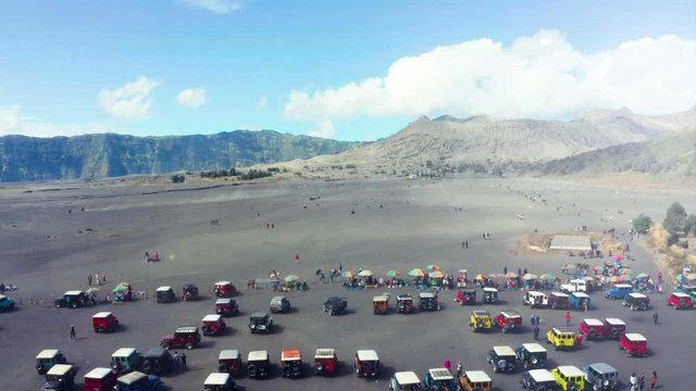 East Java, Indonesia - September 04, 2019: Beautiful aerial view of tourism jeep gather around sea of the sand in Mount Bromo national park. Shot in 4k resolution