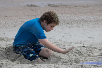 Young boy on beach making sand castle