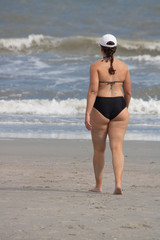 Woman walking toward ocean waves from beach
