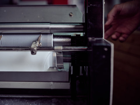 Unrecognizable worker using pressing machine in printing house