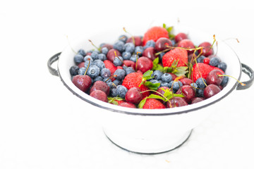Colander Filled with Various Berries in White Tile Sink