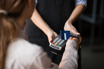 Close up young woman paying by contactless credit card