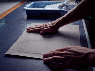 Bookbinder imposing fabric on cover for book