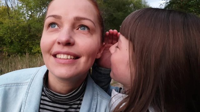 daughter whispers secrets to her mother , family relationships