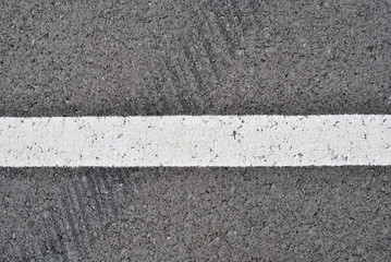 Fototapeta premium Asphalt texture with white line and tire marks . Top view