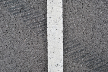 Asphalt texture with white line and tire marks . Top view