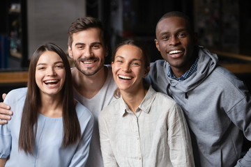 Head shot portrait of smiling diverse friends sitting in cafe together