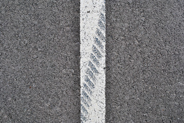 Asphalt texture with white line and tire marks . Top view