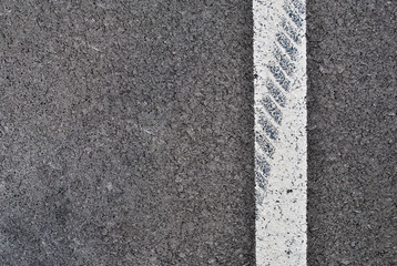 Asphalt texture with white line and tire marks . Top view