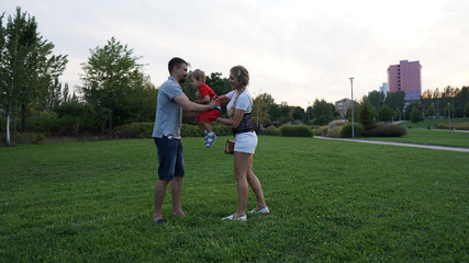 Happy family - dad, mom and little son in the park in summer.