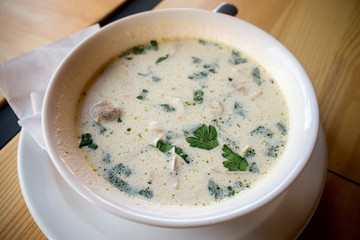 Mushroom soup in white plate on wooden table closeup