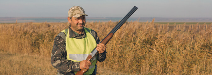 Hunting period, autumn season open. A hunter with a gun in his hands in hunting clothes in the...