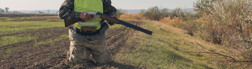 Hunting period, autumn season open. A hunter with a gun in his hands in hunting clothes in the autumn forest in search of a trophy. A man stands with weapons and hunting dogs tracking down the game.	