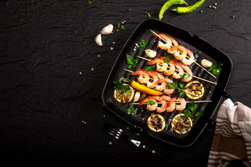 Prawns Shrimps roasted on pan with lemon, garlic and herbs on black background. Top view with copy space.