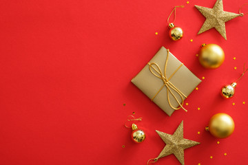 Top view golden Christmas decorations on red background. Flat lay gift box, stars, balls,...
