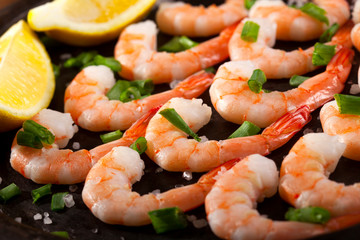 Prawns Shrimps roasted on pan with lemon, garlic and herbs on black background.
