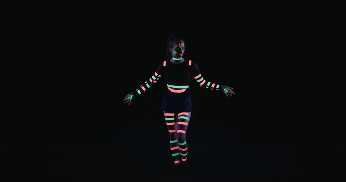 Studio, slow motion, female neon-clad dancer dancing in blacklight, London