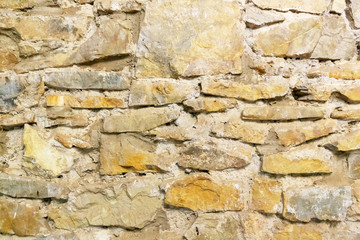 A wall of natural stone, sand-colored cement, grey seams. Background image.