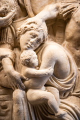 Detail of ancient engraved sculpture on marble showing woman protecting child