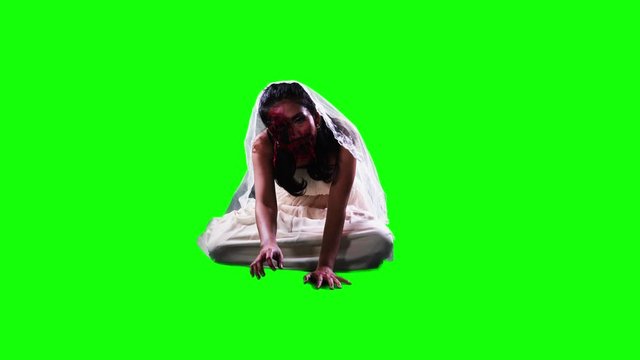 Scary female zombie with wounded face looking and crawling to the camera in the studio. Shot in 4k resolution with green screen background