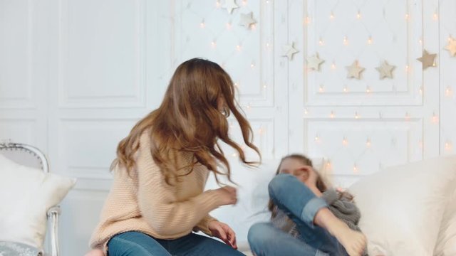 Happy girl and mom dancing in bed on new year holiday.