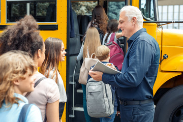 Classmates going into school bus while driver checking attendance smiling happy close-up
