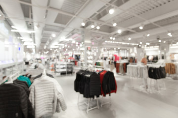 Sale and seasonal change of collection. Blurred View of fashionable clothing store in shopping...