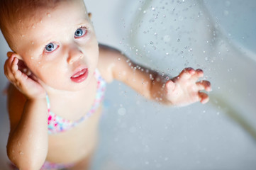 Fototapeta premium baby girl in a swimsuit in the shower