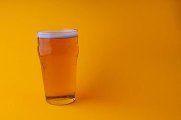 Glass of beer on a orange background with space for graphics or text on right