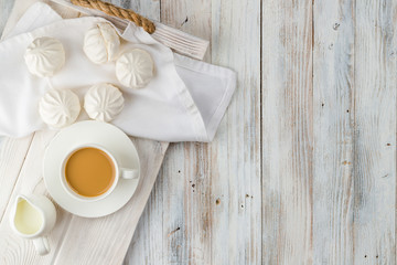 Coffee and white marshmallows on a light wooden tray with copy space