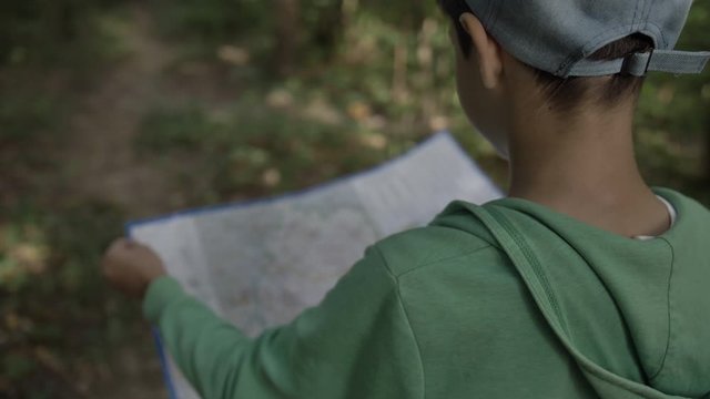 boy in the forest navigates the area using the map